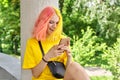 Fashionable teenager girl with colored dyed hair with a smartphone outdoors. Royalty Free Stock Photo