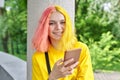 Fashionable teenager girl with colored dyed hair with a smartphone outdoors. Royalty Free Stock Photo