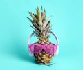 Fashionable trendy pineapple fruit with headphones and sun glasses listen to the music over bright pastel cyan background