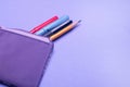 Fashionable violet pencil case with multicolored felt-tip pens, pencils and pens on lilac background. Royalty Free Stock Photo