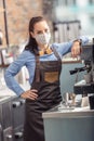 Fashionable waitress wears protective face mask while preparing an espresso in a coffee house