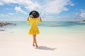 Fashionable woman with black summer hat and yellow dress on the beach