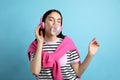 Fashionable woman with headphones blowing bubblegum on light blue background Royalty Free Stock Photo