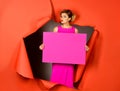 Fashionable woman with perfect makeup red lips holds empty pink board for inscription text. Fashion model in pink dress emerging