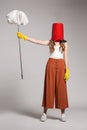 Fashionable woman with a red bucket on her head holding a mop. Royalty Free Stock Photo