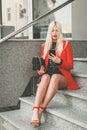 Fashionable woman sitting on stairs and using mobile phone Royalty Free Stock Photo