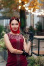 A fashionable woman with sunglasses, in a red dress and a scarf, stands beautifully on the street Royalty Free Stock Photo