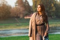 Fashionable woman walking in city park. Beauty and fashion. Stylish girl wearing trendy dress and coat Royalty Free Stock Photo