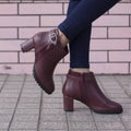 Fashionable woman wearing bordeaux colored elegant and beautiful leather heels decorated with belts