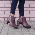 Fashionable woman wearing bordeaux colored elegant and beautiful leather heels decorated with belts