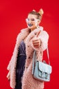 Fashionable woman wearing pink fluffy coat and blue bag