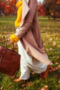 Fashionable woman wearing stylish clothes and accessories walking in fall park. Autumn female outfit.
