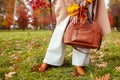 Fashionable woman wearing stylish clothes and accessories walking in fall park. Autumn female outfit.