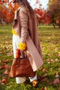 Fashionable woman wearing stylish clothes and accessories walking in fall park. Autumn female outfit.