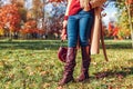 Fashionable woman wearing stylish clothes boots and accessories walking in fall park. Autumn female look Royalty Free Stock Photo
