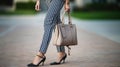 Fashionable woman wears high-heels shoes, blue cotton pants with white stripes and hold grey bag outdoors. Generative AI