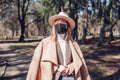 Fashionable woman wears reusable mask outdoors during coronavirus covid-19 pandemic in empty spring park