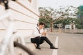 Fashionable young bearded man using a digital tablet , cheerfully smiling, watching or reading something funny, sitting on the gr Royalty Free Stock Photo