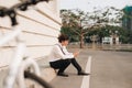 Fashionable young bearded man using a digital tablet , cheerfully smiling, watching or reading something funny, sitting on the gr Royalty Free Stock Photo