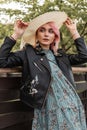 Fashionable young beautiful woman with pink hair in vintage straw hat in stylish black leather jacket in trendy blue dress near Royalty Free Stock Photo