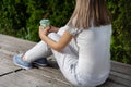 Fashionable girl sitting on bench with striped pants and holding cup of coffee. Woman resting in the park on good weather Royalty Free Stock Photo