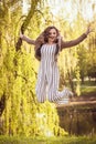 Fashionable young girl jumping happily on the background of the park