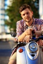 Fashionable young man riding a vintage scooter in street Royalty Free Stock Photo