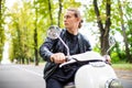 Fashionable young man riding a vintage scooter and looking back in the street Royalty Free Stock Photo