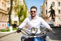 Fashionable young man riding a vintage scooter in the summer street Royalty Free Stock Photo