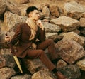 fashionable young man sitting on the rocks near the sea Royalty Free Stock Photo