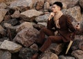 fashionable young man sitting on the rocks near the sea Royalty Free Stock Photo