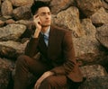 fashionable young man sitting on the rocks near the sea Royalty Free Stock Photo