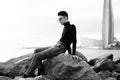 fashionable young man sitting on the rocks near the sea Royalty Free Stock Photo