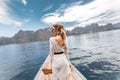 Fashionable young model in boho style dress on boat at the lake Royalty Free Stock Photo