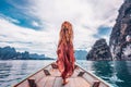 Fashionable young model in boho style dress on boat at the lake