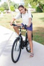 Fashionable young teen girl in shorts and t-shirt rides a bicycle in a summer park Royalty Free Stock Photo