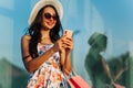 Beautiful fashionable woman holding shopping bags using mobile phone while shopping in women`s boutique on Black Friday Royalty Free Stock Photo