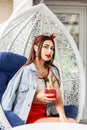 Fashionable young woman in beauty summer clothes with delicious berry-fruit lemonade sits on vintage armchair on terrace. Lovely Royalty Free Stock Photo