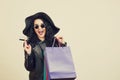 Fashionable young woman in black hat with credit card and colored shopping bags over white studio background. Royalty Free Stock Photo