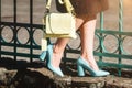 Fashionable young woman in brown dress and blue high heel shoes with yellow handbag in hand on the city streets. Fashion Royalty Free Stock Photo