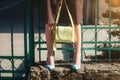 Fashionable young woman in brown dress and blue high heel shoes with yellow handbag in hand on the city streets. Fashion Royalty Free Stock Photo