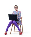 Fashionable young woman in dress and glasses sitting on chair with a laptop. White background Royalty Free Stock Photo