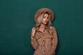 Fashionable young woman in an elegant vintage hat in a stylish shirt with curly blond hair is standing in the studio Royalty Free Stock Photo