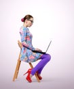 Fashionable young woman in glasses sitting on a chair with a laptop Royalty Free Stock Photo