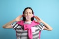 Fashionable young woman with headphones blowing bubblegum on blue background Royalty Free Stock Photo