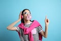 Fashionable young woman with headphones blowing bubblegum on light blue background Royalty Free Stock Photo