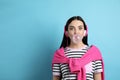 Fashionable young woman with headphones blowing bubblegum on light blue background, space for text Royalty Free Stock Photo