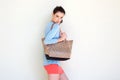 Fashionable young woman holding purse against white wall Royalty Free Stock Photo