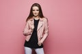 Fashionable young woman in leather jacket posing at the pink background, isolated. Stylish model girl with blond hair in Royalty Free Stock Photo