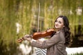 Fashionable young woman playing the violin in the park